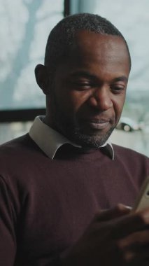 İş yerindeki masada oturan, günlük kıyafetler giyen odaklanmış Afrikalı bir adamı vurmak. Çalışan sohbeti, evdeki cihazda sosyal medya yayını. Gündüz vakti. Kapalı