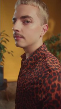 Genç adam omzunda Lgbt bayrağı tutuyor ve kameraya duygusal bakıyor. Dikey çekim