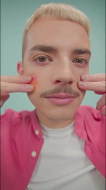 Gülümseyen adamın dikey portresi kameraya bakar ve yüzüne Lgbt bayrağı çizer.