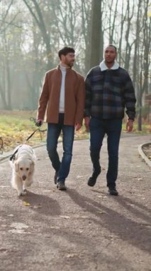 Sonbaharda parkta köpekle konuşan ve gezen çok ırklı eşcinsel çifti çekmek