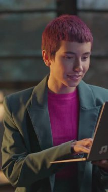 Pembe saçlı genç bir kadın geceleri LGBT etiketli dizüstü bilgisayar kullanıyor. Düşünüyorum.