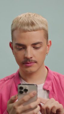 Mutlu gülümseyen adam kameraya telefonla bakar. LGBT. Telefonu parmağıyla gösteriyor.