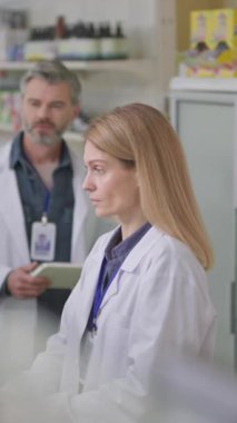 Erkek eczacı doktor ve kadın danışman bilgisayarla konuşuyor. Birlikte eczanede çalışan viral tedavinin tıbbını tartışıyorlar. Modern eczane.