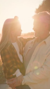 Yakışıklı, neşeli, sakallı bir babanın, sevimli kızı ile kucaklaşan, kırsalda otururken kameraya gülümseyen portresi. Sevecen bir aile..