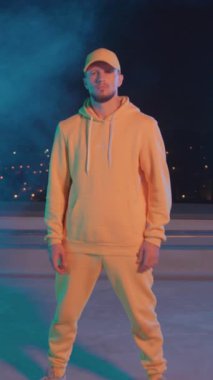 Gece dumanında poz veren parlak sarı kıyafetli yakışıklı hip hop dansçısının tam boy portresi. Sahne performansı. Sanatçı. İnsanlar.