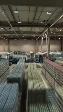 FPV görüntülü İHA lojistik park istasyonunda. Büyük bir sanayi deposu ve sıra sıra mal teslimatı. Kutular ve paketler. Çalışan personel.