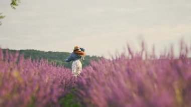 Canlı lavanta tarlalarında gezinen, dingin ve berrak mavi gökyüzünün altında güneşlenen bir kadın.