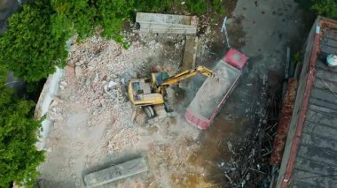 Hava görüntüsü, inşaat enkazlarıyla çevrili bir kazıcıyı gösteren devam eden inşaat faaliyetlerini yakalıyor.