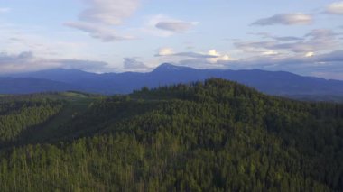 Bereketli yeşil dağların ve renkli gökyüzünün havadan görünüşü doğanın inanılmaz güzelliğini ve çeşitliliğini vurgular.