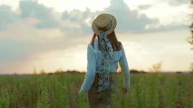 Güneş ışığında yürürken şapkalı bir kadın vurdu. Sahada kameraya döndü. Sıcak doğa tatili tatili.