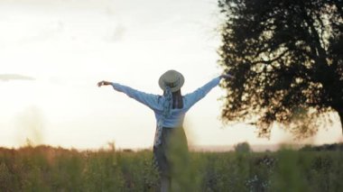 Güneş ışığında şapkalı bir kadın vurdu ellerini kaldırdı. Sıcak doğa tatili tatili. Yavaş çekimde genç bir portre.