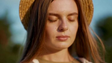 Güneşli yaz gününde şapkalı güzel bir kadın yüzü açık gözlerle gezgin kız sağlıklı açık hava özgürlüğüne çekici bir gün batımı rahatla yavaşça gülümseyen saçlar