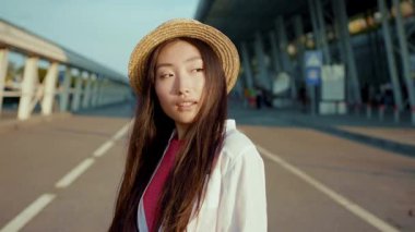Güzel gözleri olan, kameraya gülümseyen, gün batımında sokakta duran yaz şapkası takan muhteşem Çinli esmer kadın. Çekici insanlar. Hayalci kız. Moda portresi.