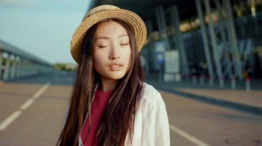 Kameraya poz veren Asyalı etnik kökenli çekici bir kadın. Güzel bir yüz hatları var. Gün batımında dışarıda yürüyor. Portreler. Moda. Kadın güzelliği..