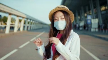Güzel görünümlü Çinli kadın kameraya gülümseyen koronavirüs maskesini çıkarıyor. Güzel, neşeli kız gün ışığında dışarıda karantina sona erdiği için seviniyor..