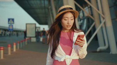 Güzel Asyalı genç kız havaalanının dışında yürürken akıllı telefon iletişim uygulaması kullanıyor. Yeni ülkeye geliyor. Çinli kadınlar dünyayı gezer..