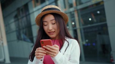 Çekici Çinli kızın akıllı telefonuyla mesaj atmasından memnun. Ekranda mutlu bir şekilde dikilirken. Güzel insanlar. Sıfır fobi. İnternet.