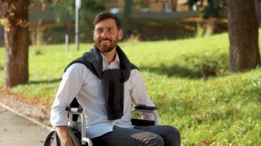 Parkta gülerek tekerlekli sandalyeye mahkum mutlu ve engelli bir adamın portresi. Felç yetersizliği pozitif engelli. Yavaş çekim