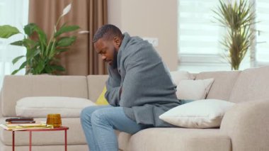 Afro-Amerikalı adam sıcak bolanketi örtbas etmek için soğuktan acı çekiyor sıcak çay içiyor ve evde hastalığını yeniyor. Sağlık sigortası. Kendini soyutlama. Grip, pandemik konsept.