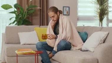 Kafkasyalı mutsuz adam Coronavirus enfeksiyonu geçiriyor battaniyeyi ısıtıyor sıcak su içiyorlar kendini izole etmek için evde kalan hastalığı iyileştiriyorlar. Sağlık hizmetleri kavramı.