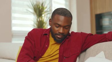 Afrika kökenli Amerikalı genç bir adam, sesli mesaj kaydediyor sosyal ağdaki telefonu kullanıyor. Kapalı alandaki kablosuz iletişim teknolojisi mikrofon hoparlörünü kullanarak gülümsemek. Yavaş çekim