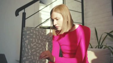 Gülümseyen genç kadın dizüstü bilgisayar kullanarak kanepede oturuyor. Ev sahibi girişimcilere bakıyor. Profesyonel rahatlama cihazı kullanıcısı yavaş çekim.