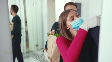 Gıda alışverişinden eve dönen genç bir çift maske ceket paketini çıkartıp salgın hastalık kapmış karantina enfeksiyonunu karantina altına alarak eve dönüyorlar.