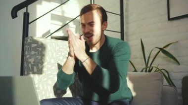 Bilgisayarı kullanan yakışıklı adam evde çalışırken mutlu oluyor. Bilgisayarda gülümsüyor, ekranda yazı yazıyor ve yavaş çekimde serbest girişimci teknolojisine bakıyor.