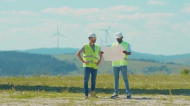 Kapatın işçiler el sıkışıyor ek yel değirmenlerini tartışıyorlar kurulum işi temiz enerji alanı enerji santrali jeneratörü rüzgar enerjisi türbinleri yavaş çekim