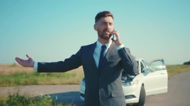 Bozuk arabanın yanında telefonla konuşan üzgün işadamı kaput yolunu açtı. Stres sorununun çözümüne yardım etti. Acil durum sigortası ağır çekimde.