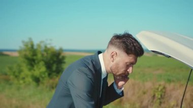 Bozuk arabanın yanındaki telefonda konuşan işadamı kaputu açtı. Stres sorununun çözümüne yardım etti. Acil durum sigortası ağır çekim.