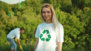 Kamera tebessümünün portresi beyaz tişört giyip geri dönüşüm işareti ile aile ekolojisi ekolojik toplum eldivenleri yavaş çekim