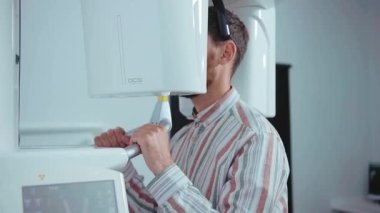 Genç yakışıklı bir adam dişçi standında makineleri kontrol ediyor. Ağzı çalışıyor. Tıbbi hasta bakımı, sağlık hizmetlerini ağır çekimde taşıyor.