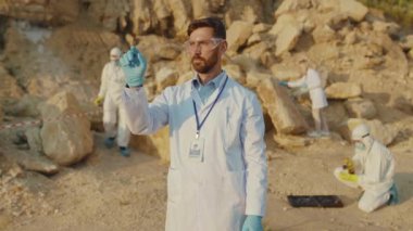 Genç adam ekoloji uzmanı koruma için şeffaf ekran fütüristik hologramı kullanıyor. Arazi yardım kimyasalları üzerinde çalışan gözlük takıyor. Toprak kirliliği üzerine çalışıyor.