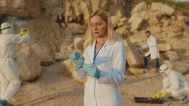 Ciddi kadın ekoloji uzmanı korunma için şeffaf ekran tableti kullanıyor. Arazi yardım kimyasalları üzerinde çalışan gözlük takıyor. Toprak kirliliği.