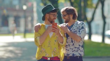 Genç iki eşcinsel gün ışığında telefon kullanıyor mutlu homoseksüel çiftler LGBT ile çıkıyor açık havada gülümseyen sevgilileri seviyor ağır çekimde çekici.