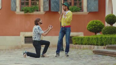 Sevimli erkek arkadaş bir dizinin üstünde durur ve nikah yüzüğünü erkeğe hediye eder mutlu eşcinsel nişanlı arkadaş nişanlısı yakın çekim mücevheri.