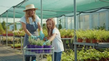 Mutlu bir kız çocuğu, annesinin bahçedeki köye çiçek dikmesine yardım ediyor. Yazın yeşil bir ailede. Kız çocuk, çocuk, eğlence evi.