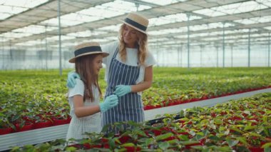 Anne çiçekli genç kız portresi. Yaz yeşili ailede serada sarılan kamera tebessümüne bakın. Kız çocuk yuvası.