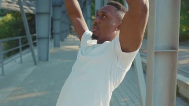 NEW YORK - 5 Eylül 2020: Yüze yakın Afrikalı Amerikalı adam trx fitness ipi ile çalışıyor açık hava vücut egzersizleri stadyum kas antrenmanları spor spor kıyafetleri yavaş çekim spor egzersizleri