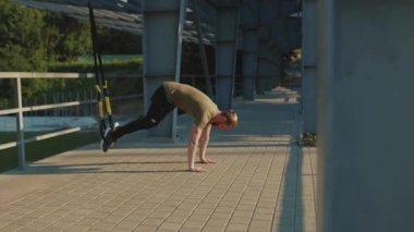 NEW YORK - 5 Eylül 2020: Trx fitness halat vücut egzersizleri ile çalışan çekici genç adam stadyum kas antrenmanlarında spor kıyafetleri spor antrenmanlarını yavaş çekim spor antrenmanlarını kapatıyor