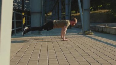 NEW YORK - 5 Eylül 2020: Gün ışığında trx fitness halat vücut egzersizleri ile çalışan genç adam stadyum kas antrenmanlarında spor kıyafetleri spor antrenmanlarını yavaş çekim spor antrenmanlarını kapatıyor