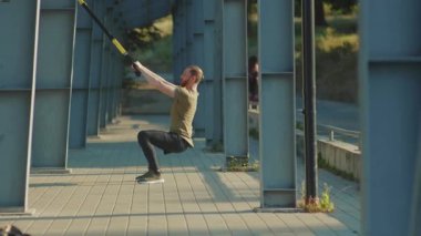 NEW YORK - 5 Eylül 2020: Trax fitness halat vücut egzersizleriyle çalışan genç adam, güneşli gün antrenörleri spor kıyafetleri spor kıyafetleri spor salonunu yavaş çekimde kapatıyor.