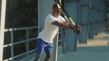 NEW YORK - 5 Eylül 2020: Trix fitness halat vücut egzersizleriyle çalışan yakışıklı Afro-Amerikan adam stadyum kaslı spor kıyafetleri spor antrenmanı ağır çekim