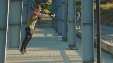 NEW YORK - 5 Eylül 2020: Trx fitness halat vücut egzersizleri ile çalışan genç ve güçlü adam stadyum kaslı spor kıyafetleri spor salonunu kapatıyorlar.