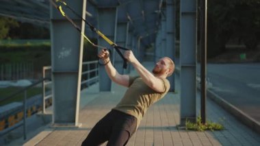 NEW YORK - 5 Eylül 2020: Trx fitness halat vücut egzersizleri ile çalışan genç ve güçlü adamı stadyum kaslı spor kıyafetleri spor antrenmanına kapatın ve yavaş çekim kapatın