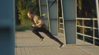 NEW YORK - 5 Eylül 2020: Trx fitness halat vücut egzersizleri ile çalışan yakışıklı genç adam stadyum kaslı spor kıyafetleri spor antrenmanlarını yavaş çekimde tamamlıyor