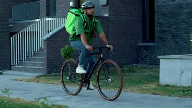 Portre kapatılıyor çekici teslimatçı sırt çantasıyla bisiklet sürüyor kurye kargo paketi ağır çekim