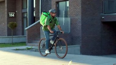 Güvenlik kaskı takmış genç bir kurye kese kağıdında yiyecek getiriyor. Çekici kadın dışarıda duruyor. Ağır çekimde yakın çekim.