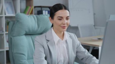 Ofisteki bilgisayar ekranına bakan memnun iş kadınının portresi. Gülümseyen bayan yönetici sandalyeye yaslanıyor ve işten sonra dinleniyor..